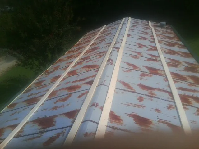 Rusted metal roof panels with new wood purlins before replacement — Storm Damage Roof Repair in Browns Valley by Roofing Brothers