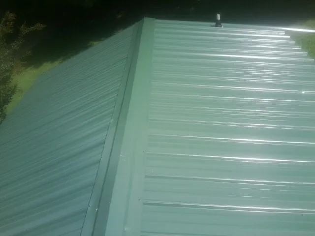 New green metal panels meeting at the ridge of a roof — Flat Roof Repair work by our crew in Browns Valley