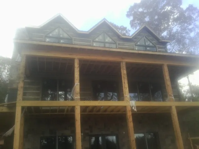 Dormers and porch framing on a large log home under construction — Roof Coating work by our crew in Browns Valley