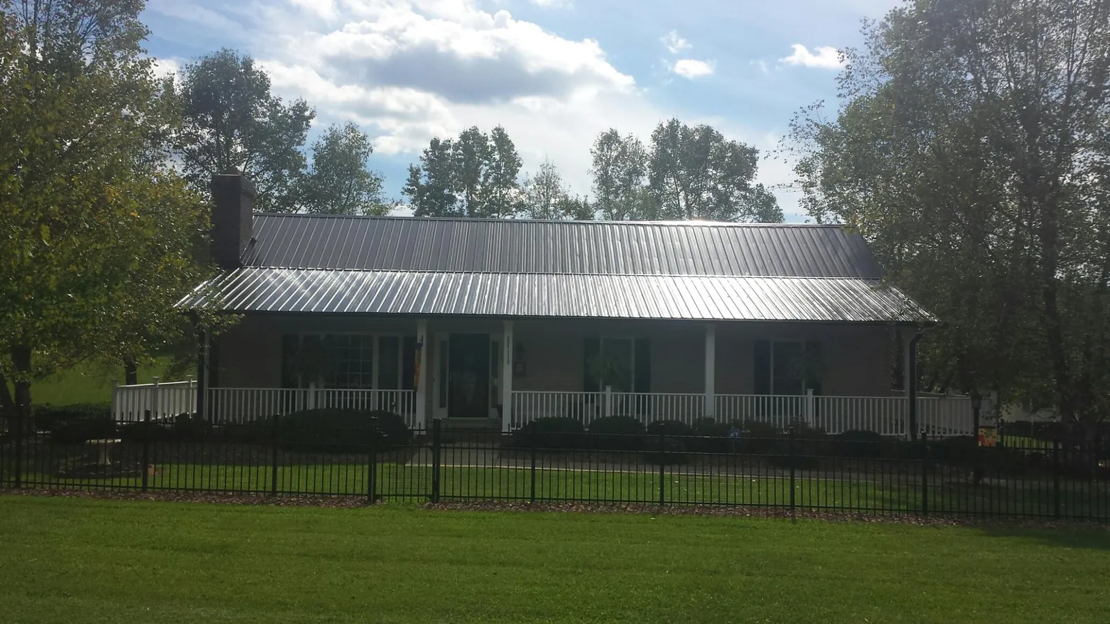 Gray metal roof on a brick ranch with a full width front porch — Gutter Guard Installation work by our crew in Browns Valley