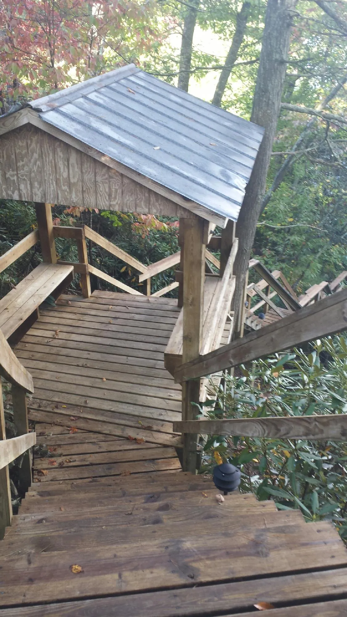 Metal roofed shelter over wooden steps on a wooded walkway — Skylight Repair & Installation work by our crew in Browns Valley