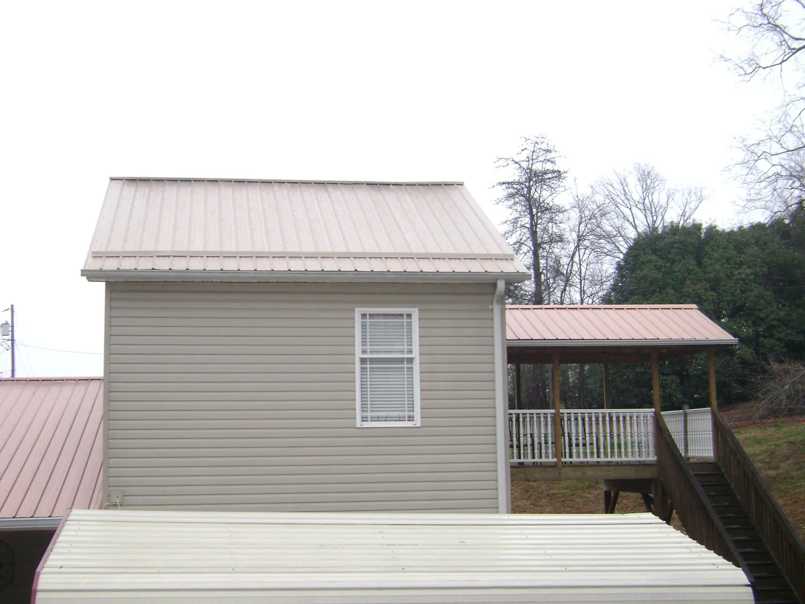 Tan metal roofs on a two story addition and attached porch, from a Roof Replacement job in Browns Valley