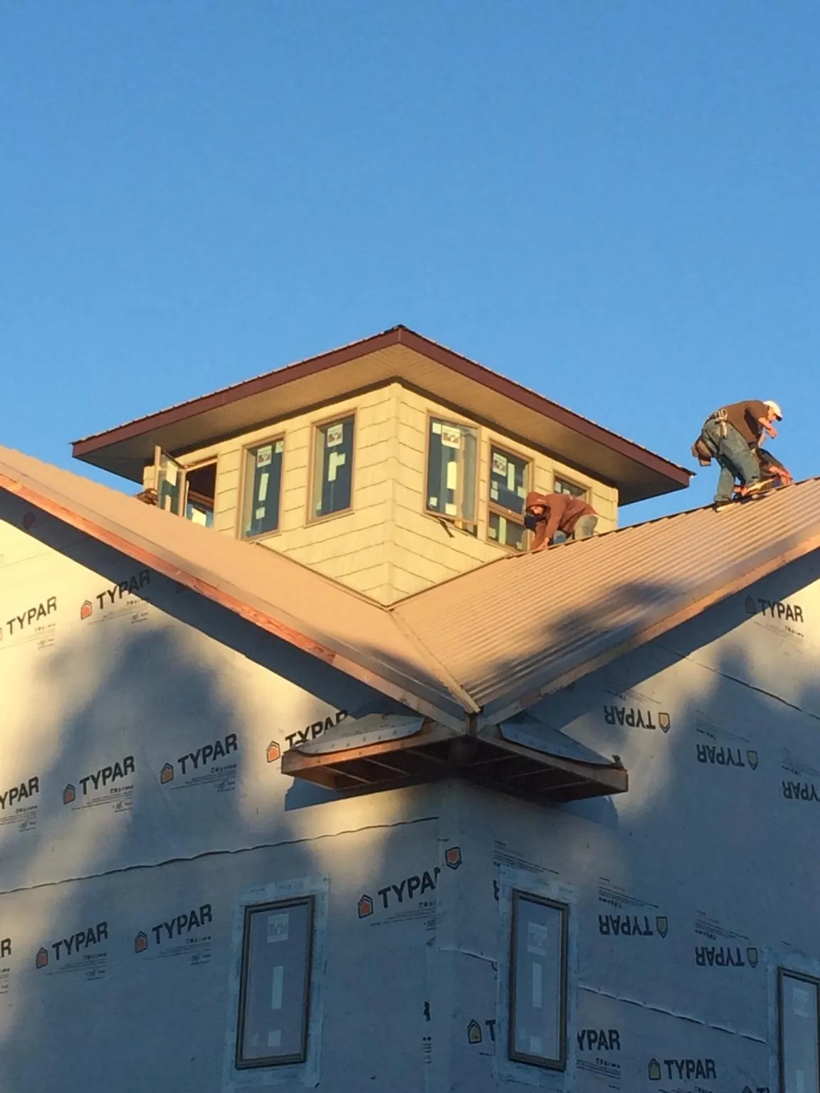 Roofers working around a rooftop cupola on a new metal roof at sunset — Roof Waterproofing in Browns Valley by Roofing Brothers